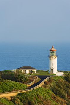 a lighthouse on top of a hill next to the ocean with a walkway leading up to it