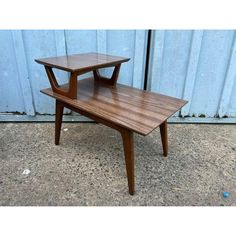 two wooden tables sitting on top of each other in front of a blue metal wall