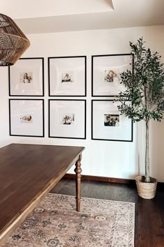 a living room with pictures on the wall and a table in front of an area rug