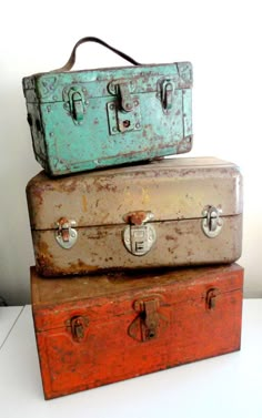 three old suitcases stacked on top of each other in different colors and sizes,