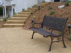 a park bench sitting in front of a house with steps leading up to the building