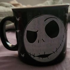 a black and white coffee mug with a jack skellingy face painted on it