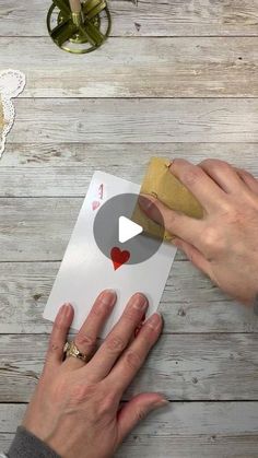 two hands are stamping hearts onto a card on a table with lace doily