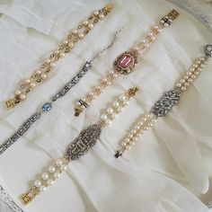 several necklaces are displayed on a white cloth with silver and gold trimmings