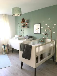 a baby's room with green walls and white furniture