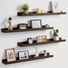 two wooden shelves with pictures, candles and other items on them against a white wall