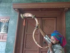 a man with a turban on talking on a cell phone while standing in front of a door