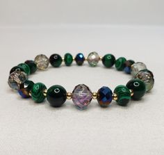 "The bracelet is made of crystals, glass, and gemstones and is beautifully handcrafted. Featuring vibrant crystal beads, malachite stone, green tiger eye, and 14 kt gold plated accent beads. With its versatile bead assortment, this bracelet goes with any outfit. You will be able to show off your unique style and make your wrist the center of attention. Most of my bracelets fit wrists between 6\" and 6.5\" in size. Before placing an order, please confirm your size. Thank you" Spiritual Crystal Beaded Bracelets For Healing, Crystal Gemstone Beaded Bracelets, Handmade Malachite Beaded Bracelets For Spiritual Use, Handmade Czech Glass Crystal Spiritual Bracelet, Handmade Malachite Spiritual Beaded Bracelets, Czech Glass Crystal Bracelet With Gemstone Beads For Gifts, Gift Crystal Bracelet With Czech Glass And Gemstone Beads, Spiritual Faceted Beads Crystal Bracelet For Jewelry Making, Crystal Beaded Bracelets With Gemstone Beads