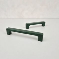 two dark green handles on a white surface with no one in the room behind them