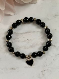 "Beautiful stretch bead bracelets with black heart charms. The bracelets shown are made with (1) 6mm white marble glass and 5mm gunmetal beads and (2) 8mm black onyx glass and 5mm silver metal beads. Both have a silver and black heart filled charm. This listing is for one bracelet with one charm. If you're looking for another color, send me a message! The bracelets shown are approximately 7\" in length." Black Braclet Aesthetic, Black Heart Bracelet, Marble Beaded Bracelets, Black Charm Bracelet, Marble Beads Bracelet, Black And White Beads Bracelet, Goth Beaded Bracelet, Black Bead Bracelet Ideas, Black Gold Beaded Bracelet