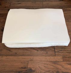 an unmade mattress sitting on top of a wooden floor next to a white pillow