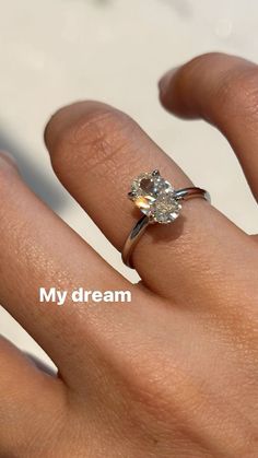 a woman's hand with a diamond ring on top of her finger and the words my dream written below it