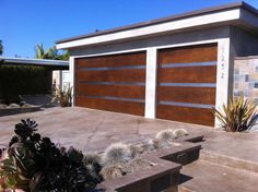 two garage doors on the side of a house with steps leading up to them and plants in front