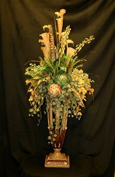 an arrangement of flowers in a vase on a black tablecloth background with a dark backdrop