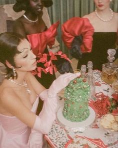 a woman in a pink dress cutting into a green cake