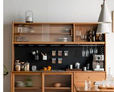 a kitchen with wooden cabinets and shelves filled with dishes on top of each shelf, next to a dining room table