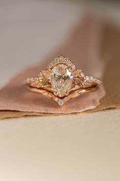 an engagement ring with a pear shaped diamond in the center on top of a piece of cloth