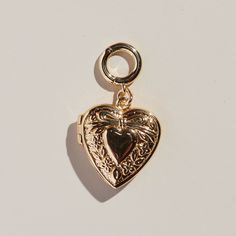 This stunning heart locket is crafted with a gleaming gold finish. With its elegant design, this locket is sure to compliment your look for any occasion. *Add this to our Paper Clip Chain Necklace or Bracelet. Or spice your ear stack up and add it to your favorite pair of Pave Huggies or Halo Hoops! Heart-shaped Brass Jewelry With Lobster Clasp, Elegant Brass Locket Necklace For Valentine's Day, Heart Pendant Metal Locket Jewelry, Metal Heart Pendant Locket Jewelry, Gold Charm Earrings For Gift, Gold Heart-shaped Jewelry With Charms, Elegant Brass Jewelry With Heart Charm, Gold-tone Metal Jewelry With Heart Charm, Gold Metal Earrings With Heart Charm