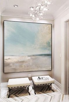 a painting hanging on the wall above two stools in front of a large art piece