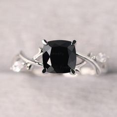 a black diamond ring with three white diamonds on the band and an oval cut stone in the center