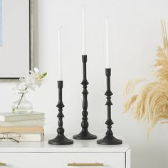 three black candles are sitting on a white dresser