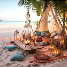 a table with candles and pillows on the beach