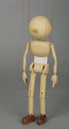 a wooden toy with strings attached to it's head and legs, standing in front of a gray background