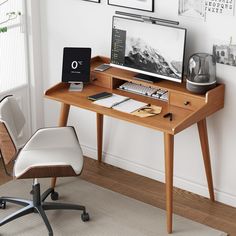 a wooden desk with a computer monitor and keyboard on it next to a white chair