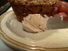 a white plate topped with a muffin next to some grapes and a knife on top of it