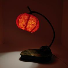 a red lamp sitting on top of a wooden table next to a piece of wood