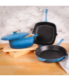 three cast iron pans and one skillet are sitting on a cutting board next to each other