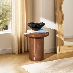 a table with a book on top of it in front of a mirror and window