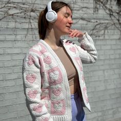 a woman wearing headphones standing in front of a brick wall with her eyes closed