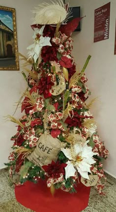 a christmas tree decorated with red and white flowers, feathers and burlap tags