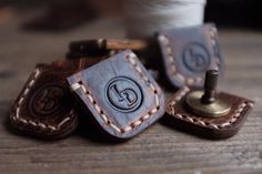 three pieces of leather sitting on top of a wooden table next to spools of thread