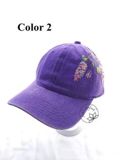 a purple hat with flowers embroidered on the front and side, sitting on top of a white