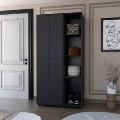 a black cabinet in the middle of a room with white walls and wooden floors, next to a bed