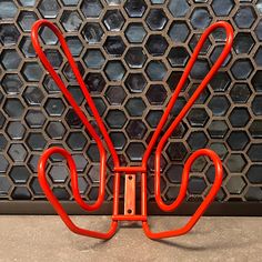 an orange umbrella stand on the ground in front of a wall