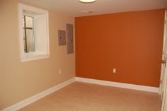 an empty living room with orange walls and white trim on the door, window, and light fixture