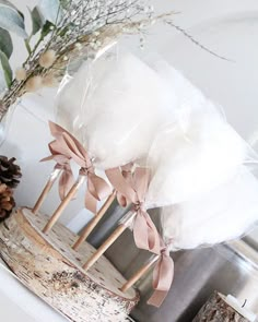 three wooden sticks with bows tied to them on top of a white mantle next to a pine cone