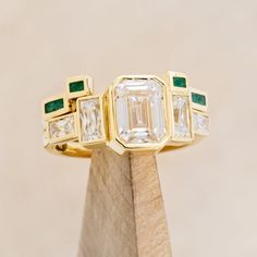 Product Details Ring Style: The Greta" is an art deco-style bezel set moissanite women's engagement ring with moissanite accent stones and a malachite stacking band. Many other center stone options are available upon request. Center Stone: 8x6mm Emerald Cut Moissanite Materials: 14K white gold engagement ring featuring 3 main moissanite stones, baguette moissanite side stones, and a malachite inlay tracer. Customizable: Because each ring is handcrafted to order, we can customize yours using unique materials, gemstones, or design features, often without any added cost! We can even use personal materials that you send! Basic customizations, such as material swaps, can be accommodated by simply adding a request in the “Custom Requests” section during checkout. For more extensive customization Unique Bezel Set Engagement Ring, Unique Emerald Cut Engagement Rings, Brand Identity Jewelry, Ashley Miller, Engagement Ring Stack, Non Traditional Wedding Ring, Emerald Cut Moissanite Engagement Ring, Bezel Set Engagement Ring, Art Deco Wedding Band