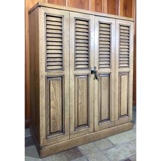 a large wooden cabinet with shutters on the front and side doors, sitting in a room