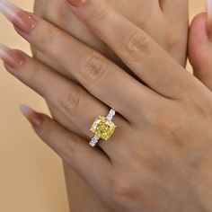 a woman's hand holding a yellow diamond ring