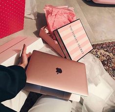 a person sitting at a table with an apple laptop in front of them and two boxes on the floor