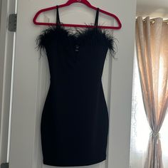 a black dress hanging on a door with a red hanger in front of it