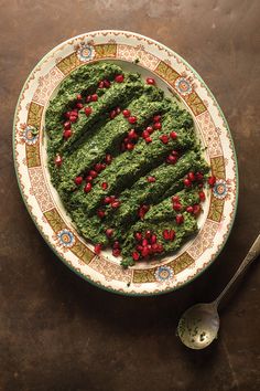 a plate with spinach and cranberries on it next to a knife and fork