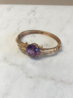 METAL: 14kt Yellow Gold LENGTH: inches GEMSTONE: 16mm Round Amethyst approx 4.00ctw WIDTH: 6mm WEIGHT: 22.8 grams This Vintage/Estate 14kt Yellow Gold Bangle has a hinged clasp opening, with a 16mm Round Faceted Amethyst Gemstone 4.00ct approx total weight with floral design pattern surrounding the Gemstone. FREE SHIPPING Regular Retail Price: $3,550.00 Estate Style 14k Gold Oval Jewelry, Estate Style Collectible Gemstone Jewelry, Yellow Gold Estate Jewelry, 14k Gold Bracelet With Birthstone For Formal Occasions, Formal 14k Gold Bracelet With Birthstone, Estate Style 14k Yellow Gold Jewelry, Formal Round Amethyst Bracelets, Formal Amethyst Round Bracelets, Estate Style Round Jewelry Gift