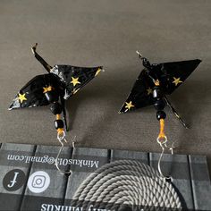 Origami Crane Earrings. Handmade Foil Candy Wrapper Earrings. Cranes Made From Black Baci Foil Wrapper With Classic Gold Stars. Black Porcelain Bead Accents. Self-Hooking Fishhook Style Earrings. Cranes Have Been Sealed With Water Based Gloss Sealant. This Will Help Maintain Their Shape And Structure, But Care Should Still Be Given As Foil Underneath Is Delicate And Susceptible To Crushing/Being Misshapen By Force. Full Length From Hook Is 2.5in Crane Earrings, Yellow Daisy Flower, Hello Kitty Earrings, Candy Wrapper, Black Porcelain, Hammered Hoop Earrings, Origami Crane, Teardrop Dangle Earrings, Color Jewelry