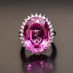 The feminine appeal of our Fantine Pink Sapphire Diamond Ring is undeniable. From the one carat of dainty, individually-set diamonds along the edge of the setting, to the incredible facet-rich depths of the substantial 25 carat center stone, this pink sapphire cocktail ring is made to be admired. With every subtle movement of your hand, this diamond-accented piece glitters brilliantly, showcasing the rich, saturated pink hue at the heart. Supported by a modern basket-style setting in smooth whit Pink Sapphire Diamond Ring, Ring Day, Sapphire Cocktail Ring, Red Sapphire, Pink Diamonds, Pink Sapphire Ring, Ingredients List, Natural Diamond Ring, Cash Out