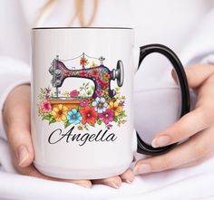 a woman holding a coffee mug with an embroidered sewing machine on it and the words, angelia